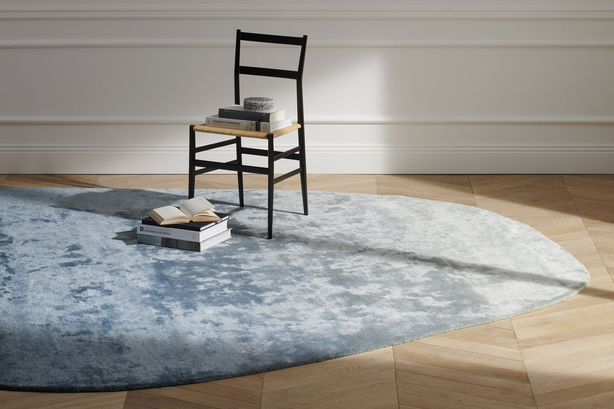 Tapis Aral en soie de bambou - Cassina-en situation sur parquet, tapis bleu et chaise noire-Cassina