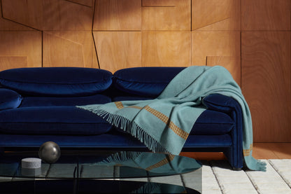 Plaid Naos en laine et cachemire - Cassina-en situation sur un canapé bleu nuit, plaid turquoise-Cassina