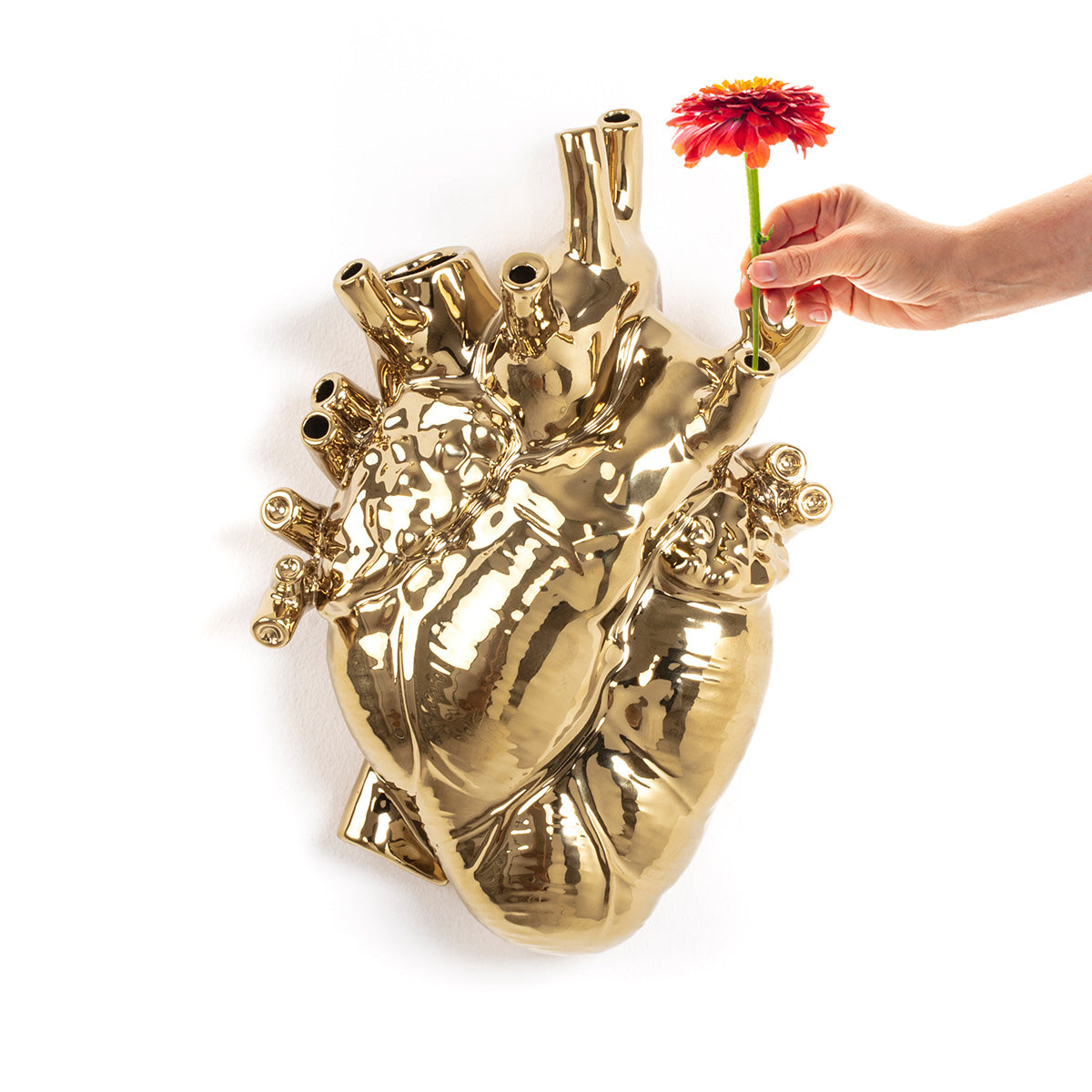 Vase coeur Love In Bloom Giant doré de Marcantonio - Seletti-cœur doré vu de trois quarts, une main y glisse une rose-Seletti