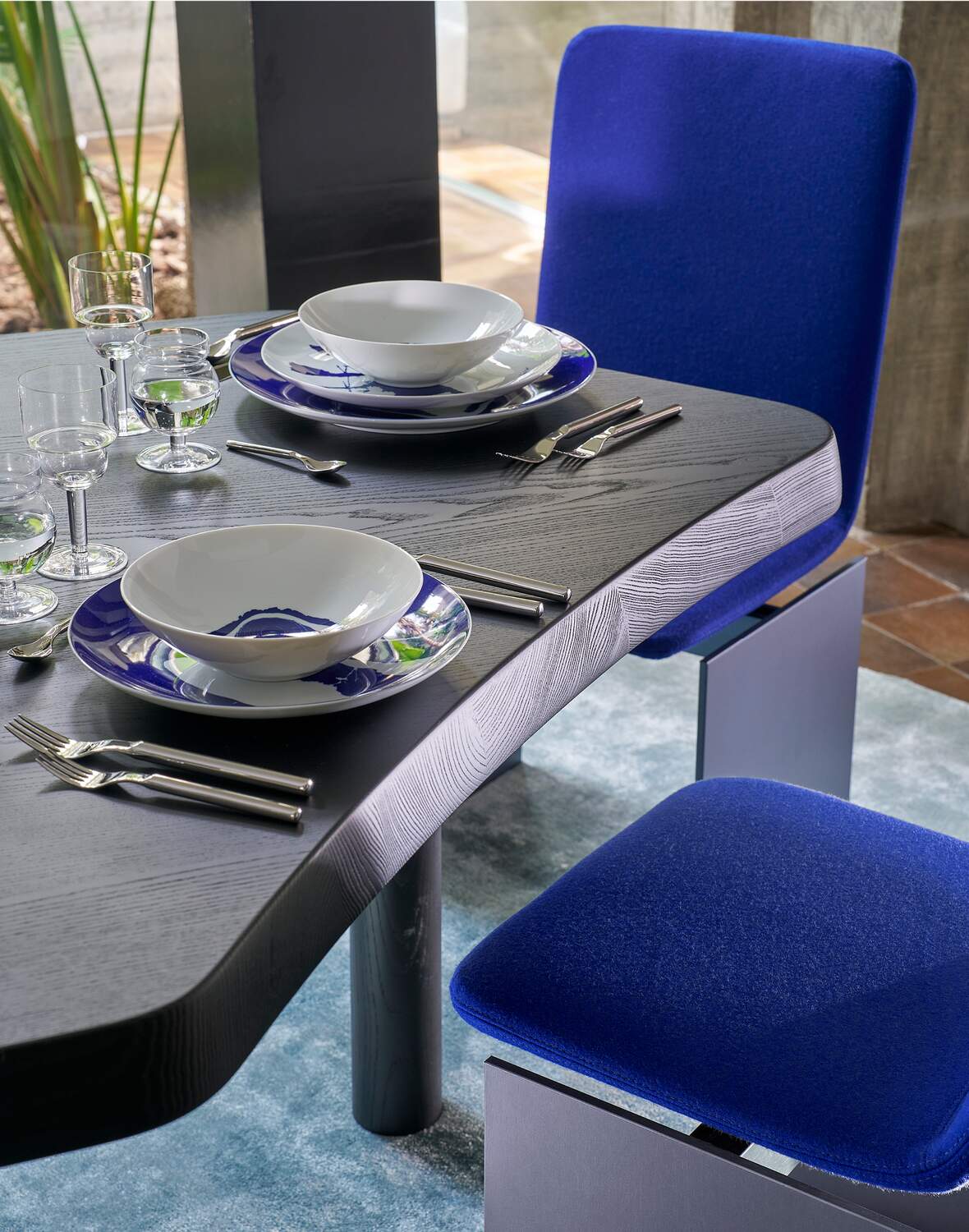 Table 545 Montparnasse de Charlotte Perriand - Cassina-table noire servie, assiettes bleues et chaises bleues-Cassina