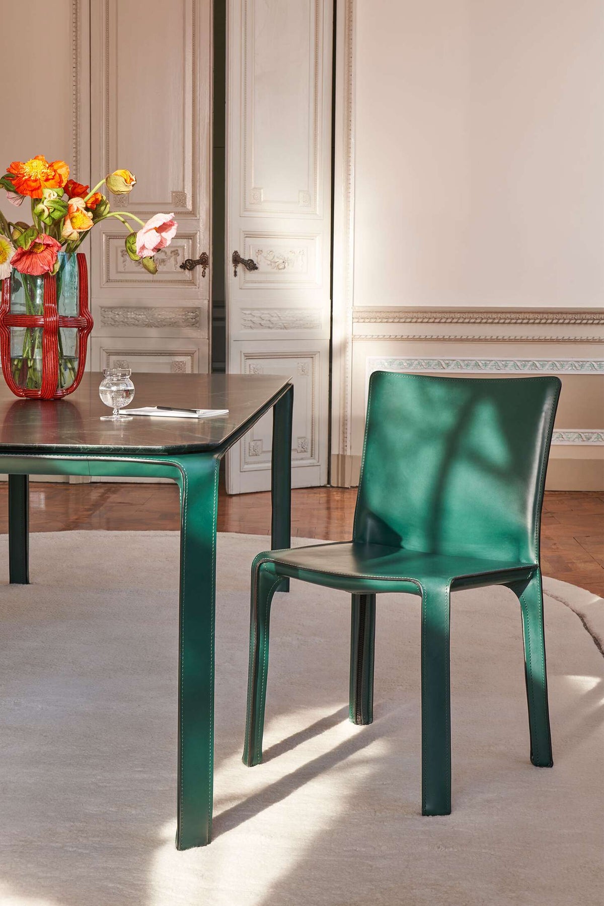 Chaise CAB 412 de Mario Bellini - Cassina-chaise en cuir vert devant une table, ambiance Cassina